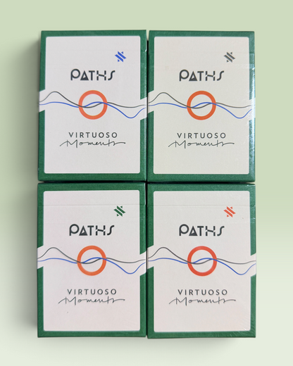 Four identical boxed cards arranged in a 2x2 grid on a pale mint background. The boxes are dark green with white front panels, featuring the brand name PATHS and the product name Virtuoso Moments, plus a central orange circle and blue line graphic.